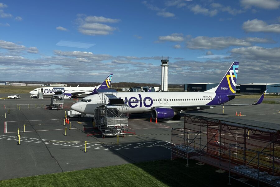 Avelo Airlines planes parked at an airport with a control tower.