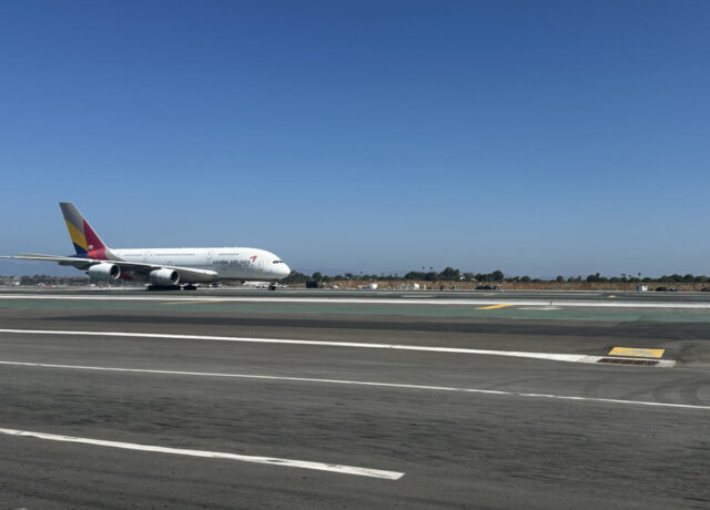 Airplane taxiing on runway under clear blue sky