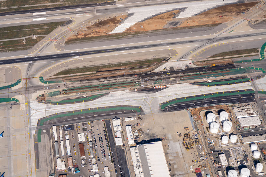 Aerial view of airport runways with adjacent construction and industrial buildings.