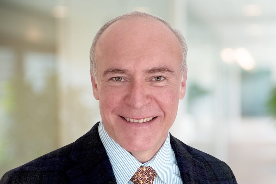 Fabio Bendana smiling in an office setting wearing a suit and tie