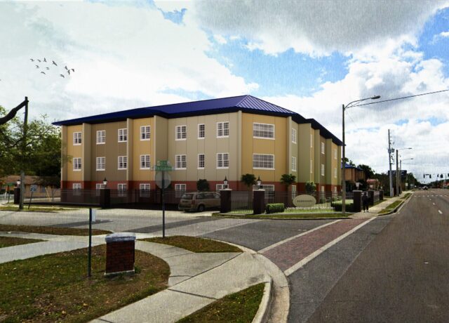 Three-story beige building with a blue roof, located at a street corner.