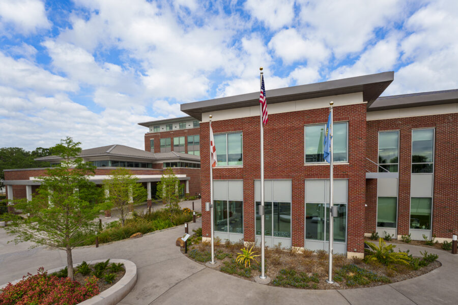 City of Kissimmee City Hall, red brick exterior, flags flying, landscaped entrance, partly cloudy sky