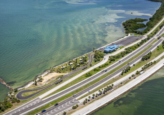 Aerial view of Skyway Rest Area with building, parking, and ocean.